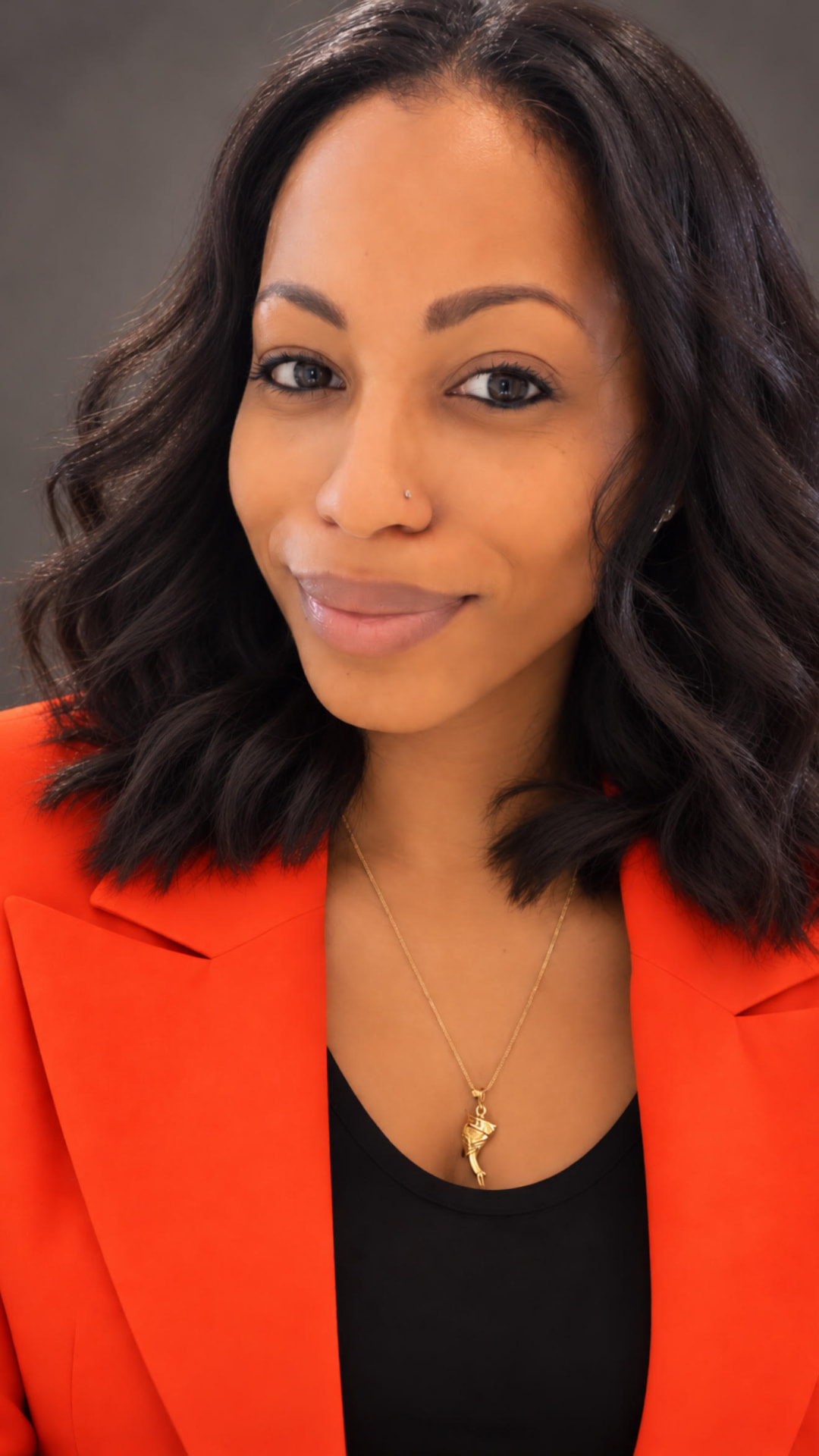 Bianca M. Forde wearing a warm orange blazer.
